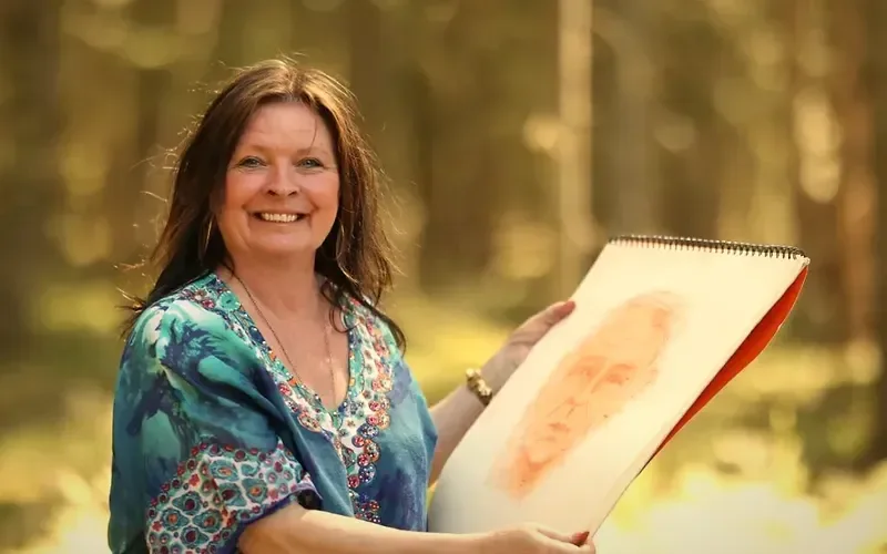 Mia Ottosson in the forest holding one of her spirit portraits
